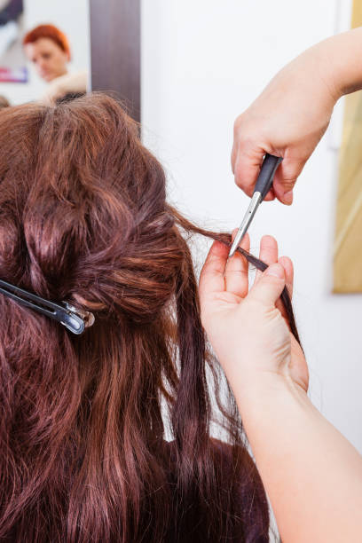 Hairdresser removing hair extensions of customer with pliers.