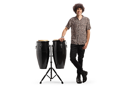 Full length portrait of a guy leaning on conga drums isolated on white background