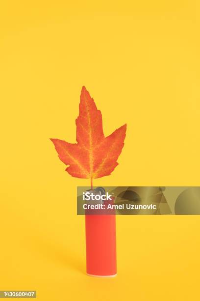 A Red Lighter And A Maple Leaf On A Yellow Background Autumn Colors Creative Minimal Concept Stock Photo - Download Image Now