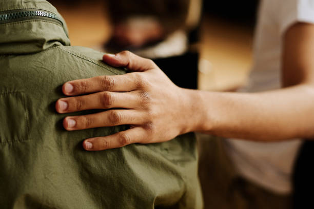 Hand of young supportive man consoling his friend with post traumatic syndrome Hand of young supportive man consoling his friend or one of attendants with post traumatic syndrome caused by dramatic life event mental health stock pictures, royalty-free photos & images