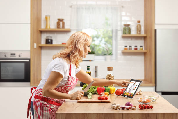 istock Mature woman cooking on a counter and watching a video on a digital tablet inside a kitchen 1430605360