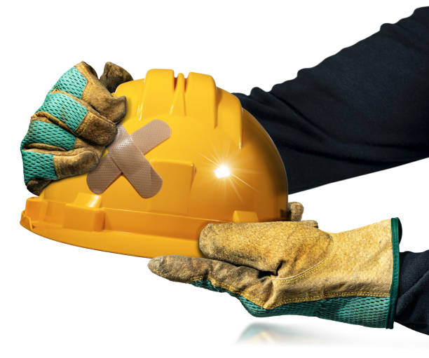 Gloved Hands Holding an Orange Safety Helmet with Cross Band Aid stock photo