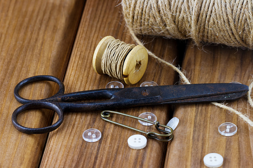 Close-up view of old sewing kit: scissors, twine, thread, buttons, on wooden background
