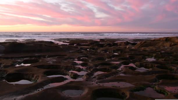 istock Eroded tide pool rock formation in California. Sunset sky reflection in water. 1430615146