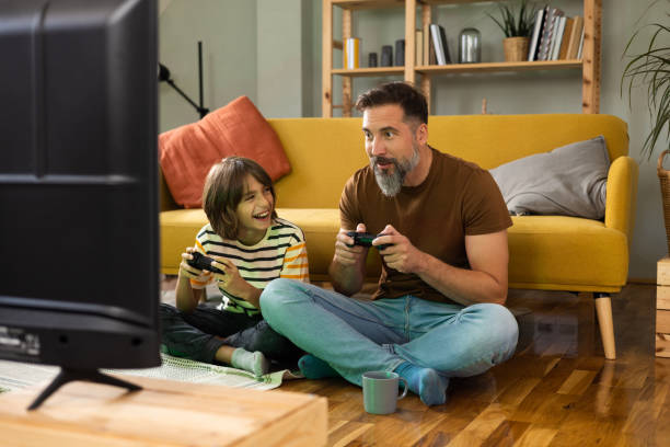 Boy and his dad gaming and having fun at home stock photo