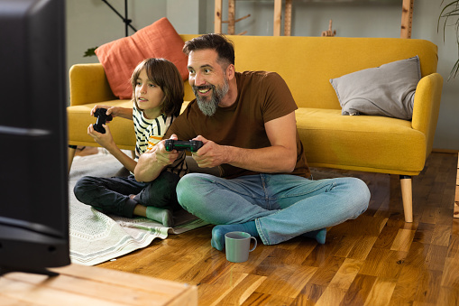 Father and son relaxing at home and playing video games