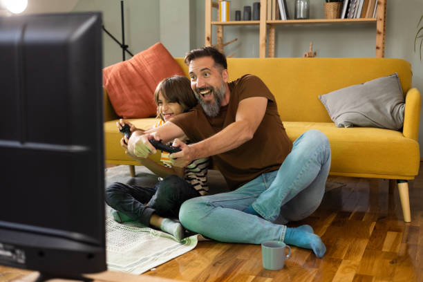 istock Man having fun with his boy while playing video games 1430616814