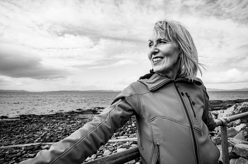 Mature woman on the coastline at the village of Portmahomack in the Easter Ross region of Scotland.