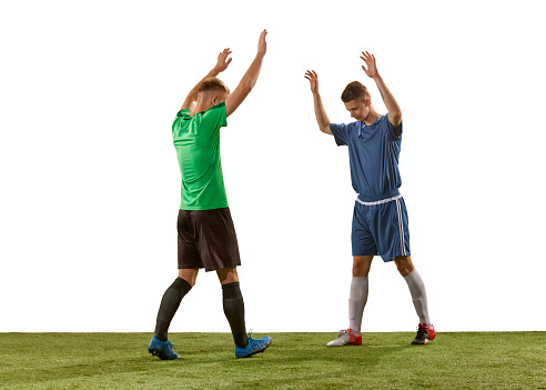 Salutation. Rival soccer players wearing blue and green football kits greeting each other before game isolated over white background. Sport, competition, communication and match concept.