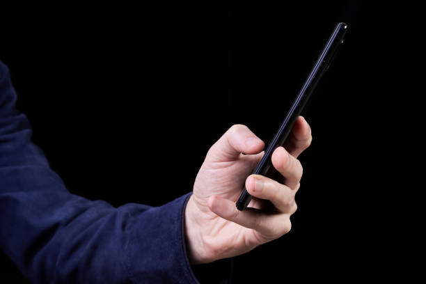 istock Man looking at smartphone screen on dark background 1430625772