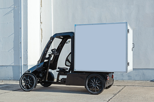 A modern electric delivery Quadracycle bike with a blank white cargo box with copy space for advertising.