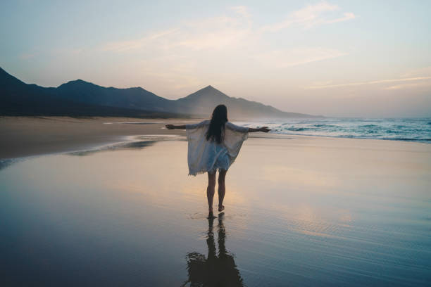 giovane donna che gode del tramonto sulla spiaggia - concetto di wonderlust - light sea low tide fuerteventura foto e immagini stock