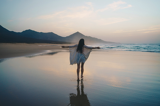 Young woman enjoying sunset on the beach - wonderlust concept