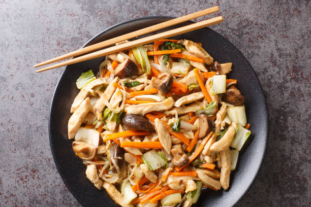 Delicious stir-fry of tender chicken and crunchy vegetables, chop suey close-up in a plate. Horizontal top view Delicious stir-fry of tender chicken and crunchy vegetables, chop suey close-up in a plate on the table. Horizontal top view from above chopping food stock pictures, royalty-free photos & images