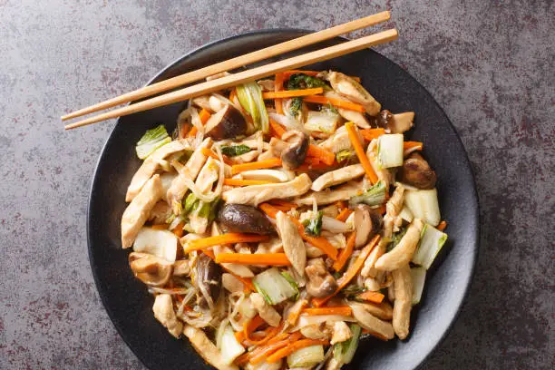 Delicious stir-fry of tender chicken and crunchy vegetables, chop suey close-up in a plate on the table. Horizontal top view from above