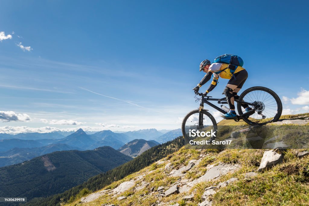 Starting the mountainbike downhill. An experienced and well equipped male mountainbiker is on his way downhill on a narrow footpath from a summit of the Carinthian mountains nearby Lake Weissensee. The region is very famous in wintertime for ice skating and in summertime for hiking and mountainbiking.
Canon EOS 5D Mark IV, 1/1000, f/2,8, 16 mm. Mountain Biking Stock Photo