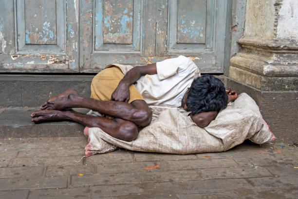 Beggar homeless man laying on the sidewalk in Mumbai in India stock photo
