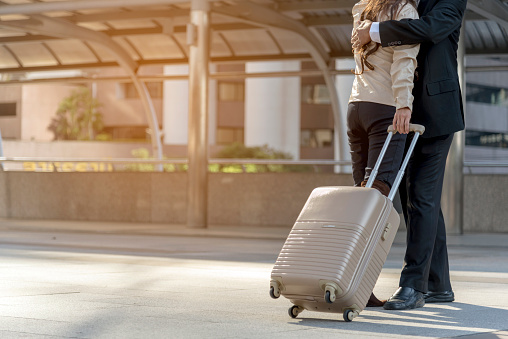 Businesspeople couple lover walking with luggage in business trip. Honeymoon business trip hug together on boarding arrival terminal. Business travel trip holding suitcase at airport couple traveller