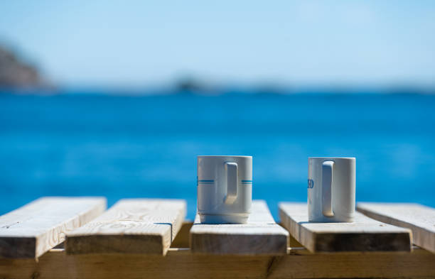 istock Two mugs on a wooden table by the sea. 1430659263