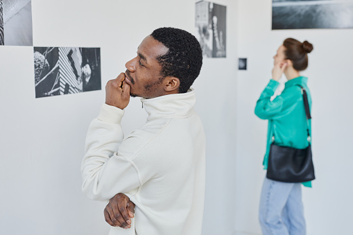 Minimal side view portrait of two people looking at photography in art gallery, copy space