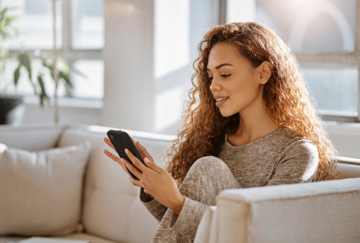 Social media, woman and phone typing, dating profile and smartphone on living room sofa. Happy Brazil person reading mobile apps, tech website and internet connection, online notification and network