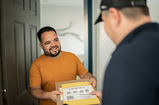 Mid adult man receiving package at home entrance
