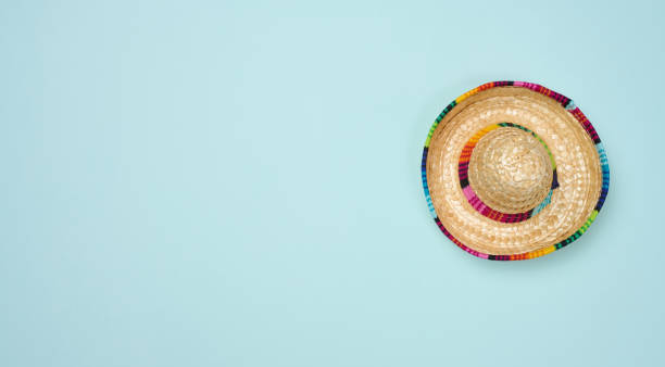 Straw mexican hat on blue background, top view. Copy space