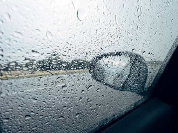 istock Car wing mirror and side window covered in raindrops during summer shower rain storm 1430673948