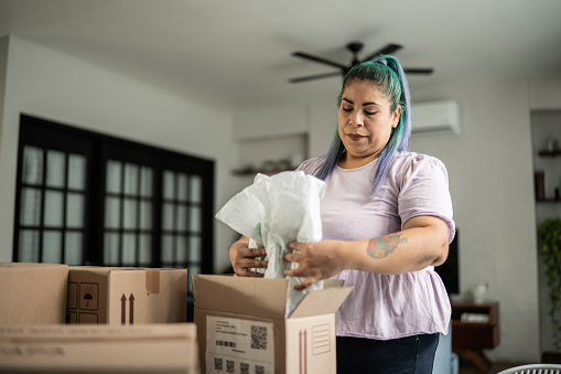 Mid adult woman arranging packages for shipment in the living room at home