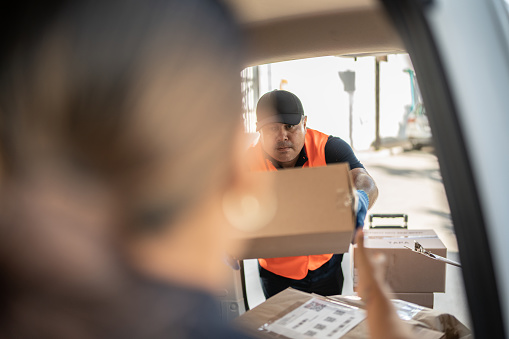 Mid adult man ordering cardboard boxes on van truck