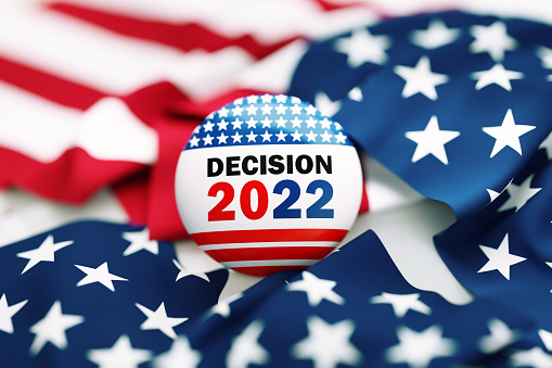 Decision 2022 written badge sitting over rippled American flag. Great use for election and voting concepts. 2022 US Midterm Election concept. High angle view.
