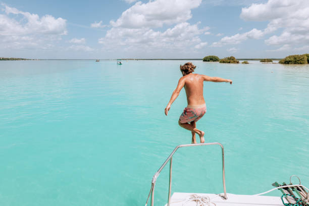 istock Young man jumps from a boat onto lagoon 1430676974