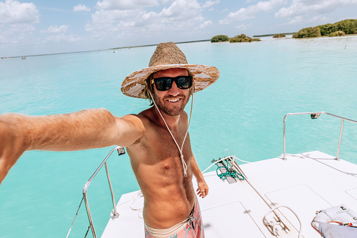 Shades of blues, solo travel male enjoying his tropical vacations.\nHappy male smiles at camera, photo memories