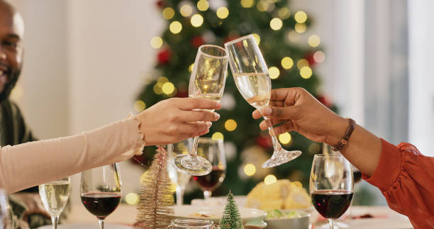 Champagne, toast and friends celebration christmas party, happy cheers while sharing a meal together in a house. Foods, family and party with people celebrating festive season and bonding at dinner stock photo