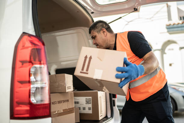 istock Postal worker organizing van truck with cardboard boxes 1430678077