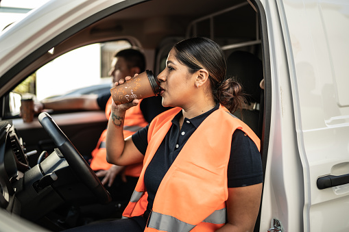 Delivery woman drinking coffee at the driver's seat