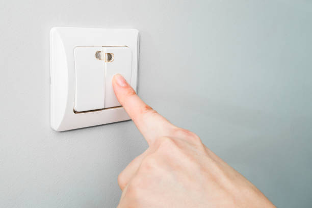 istock saving electricity. the girl turns off the light switch. close-up 1430678548