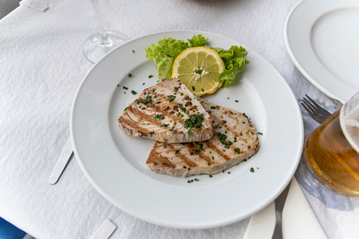 Grilled tuna steak on the table on a white plate.