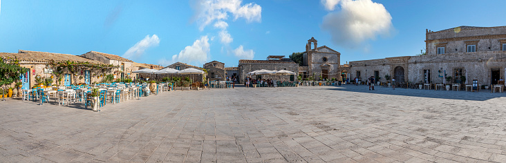 Marzamemi, Italy - 09-14-2022: Extra wide view of Piazza Regina Margherita in Marzamemi full of colors and characteristic places