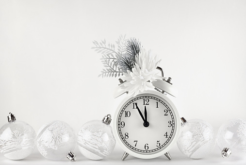 Christmas monochrome composition with festive decorations and alarm clock on white background