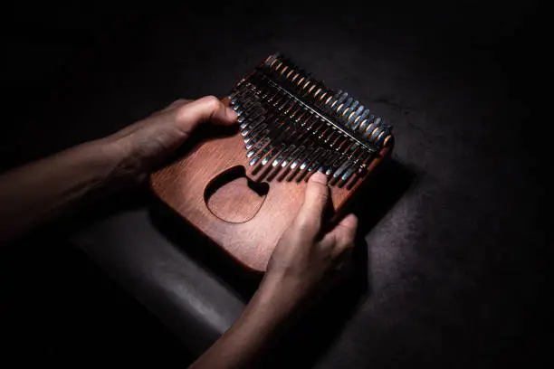 A woman's hand holds a Kalimba or mbira, an African musical instrument. Kalimba is made of wood with metal to create sound. separately on cement floor