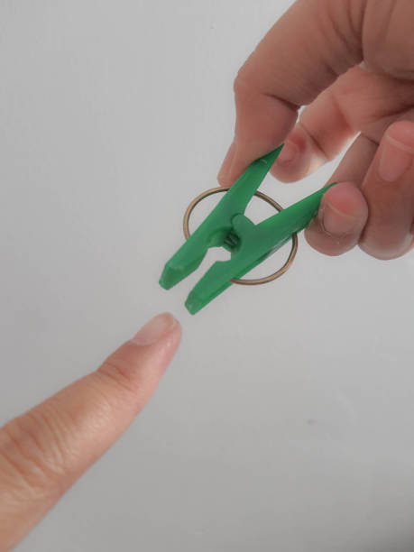 istock A hand tries to pinch his thumb using a green clothespin. 1430694202