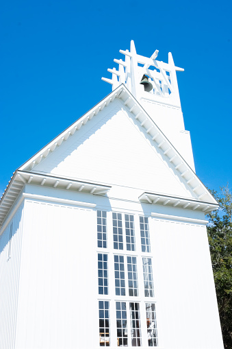 Wooden cross on a simple steeple set against a sunny summer blue sky.