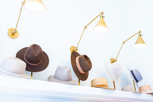 A row of multiple stylish hats in a row on a retail shelf display.