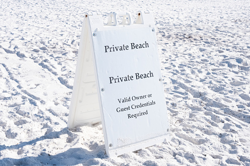 A folding private beach informational sign.