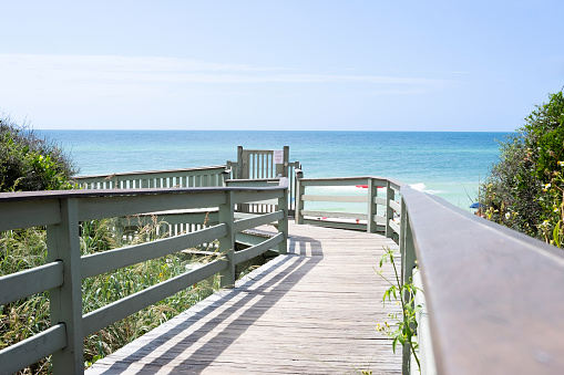 a low angle view down a wooden boardwalk leading to the beach and ocean in Rosemary Beach, Florida.