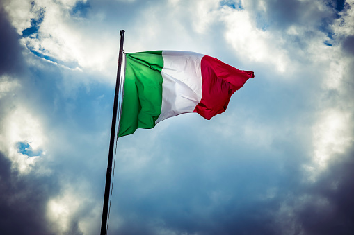 Flag of Italy pictured against cloud and sunshine