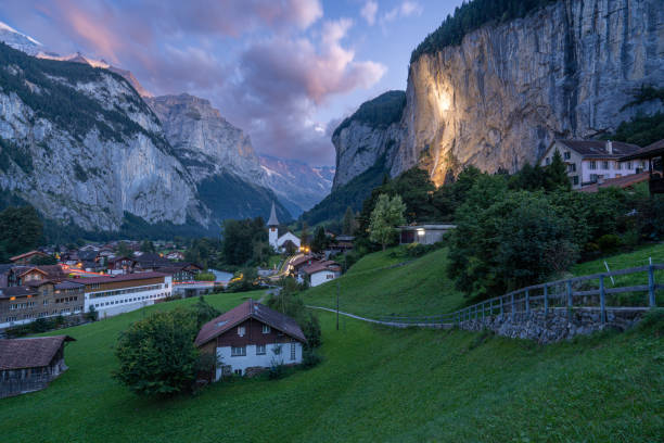 яркий закат над красивыми заснеженными швейцарскими альпами, возвышающимися над изумрудно-зеленой долиной лаутербруннен в швейцарии - staubbach falls стоковые фото и изображения