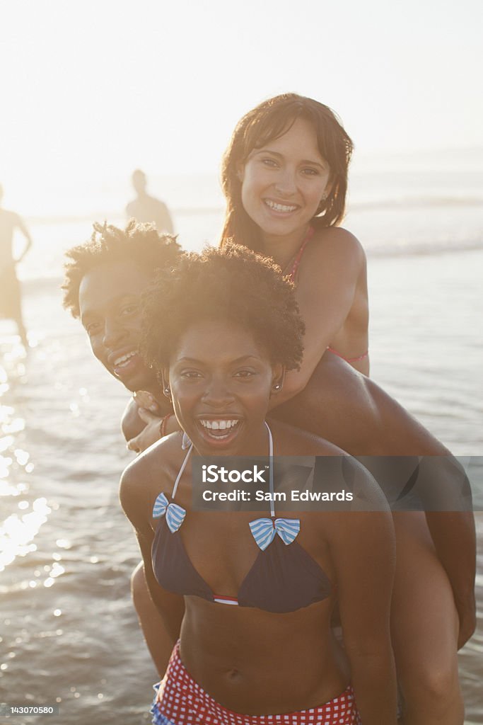 Amigos jugando en las olas en la playa - Foto de stock de 20-24 años libre de derechos