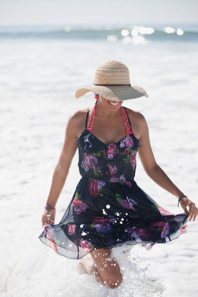 donna camminare in onde sulla spiaggia - women wading sun hat summer foto e immagini stock